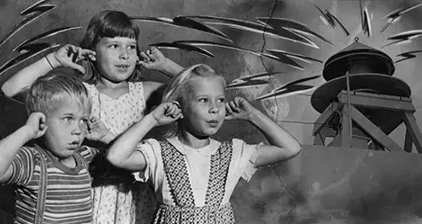 3 kids plug their ears from fireworks noise.