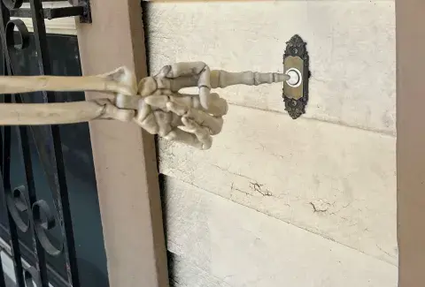 skeleton hand pushing a doorbell button