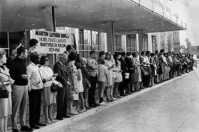 People lined up in front of a sign honoring Martin Luther King, Jr. 