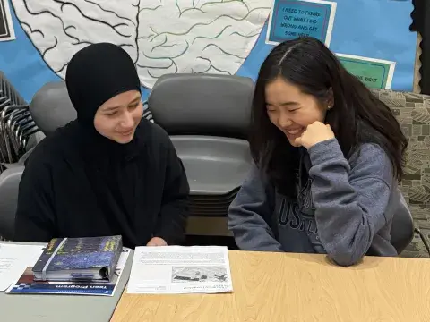 two teens looking at a book together