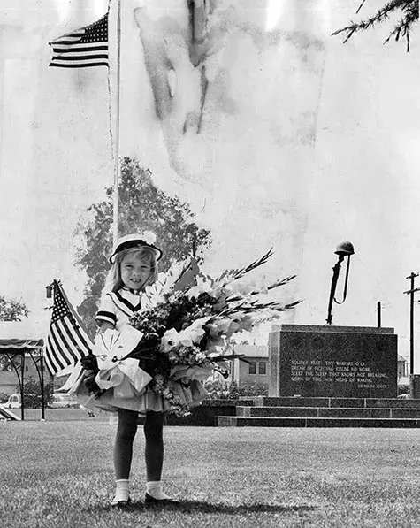Patty Peters, 4, of Encino, carries grownup-size bouquet with flag to Veteran