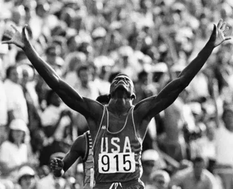 Carl Lewis raises his arms in victory 