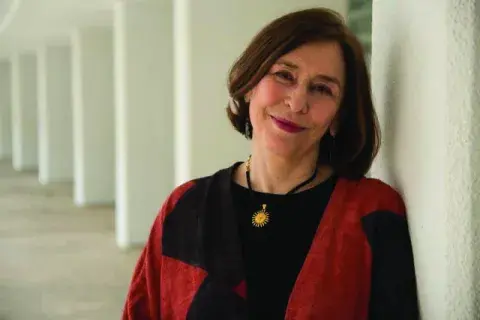 Azar Nafisi in a red and black sweater leaning against a collomnade