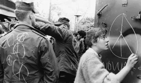 solder looking at a man drawing a peace sign on a poster