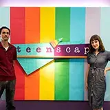 a man and a woman editor in front of the teenscape sign