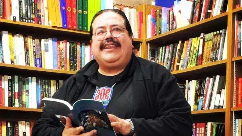 poet Francisco X. Alarcón holding a book