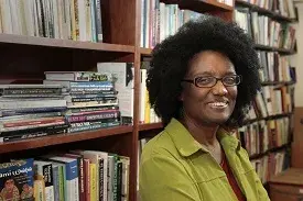 Harryette Mullen next to book shelves