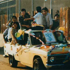 A group of Hollywood High School Vietnamese students riding a top a car in a student parade.