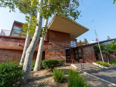 Exterior of Woodland Hills Branch Library, a brick building with trees growing in front. 
