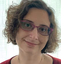 Photograph of a woman wearing glasses and smiling.