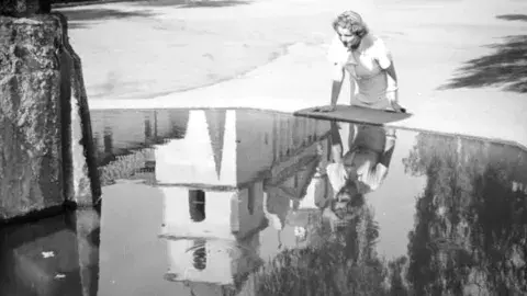 Ethel Schultheis looks into a large fountain