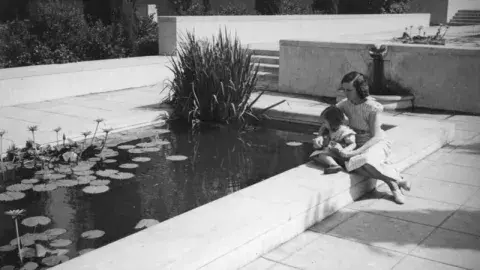 Photo of Woman and Child Sitting By Lily Pond