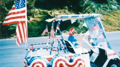A boy drives a golf cart decorated for a Fourth of July parade in San Pedro.