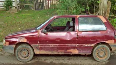 old red compact car in bad shape