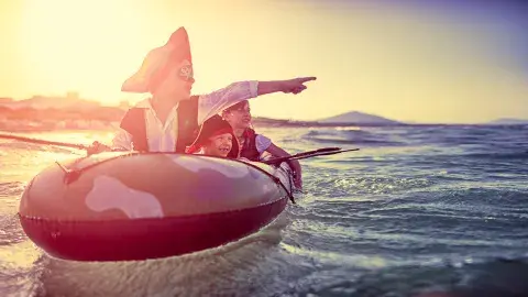 Kids dress in pirate clothes enjoying seafaring adventures while floating in a dinghy 