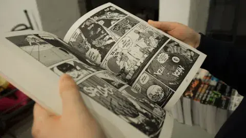 close up of hands holding open a manga book