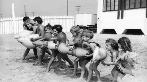 Children at the beach with floatie toys