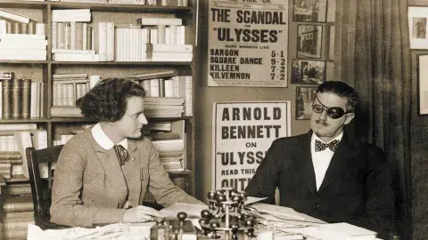 Joyce with Sylvia Beach at 12 rue de l’Odéon - 1922 known by the “Scandal of Ulysses” poster. unknown photographer; source: The Poetry Collection of the University Libraries, University at Buffalo, The State University of New York
