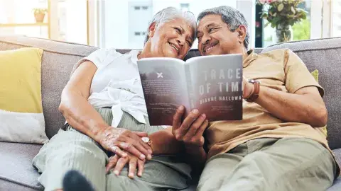 Happy, smiling senior couple on a sofa, reading a book together
