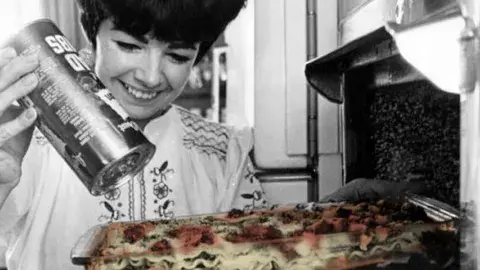 Women sprinkles cheese on lasagna