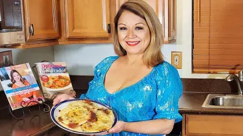 Alicia Maher holding a plate of pupusas in her kitchen