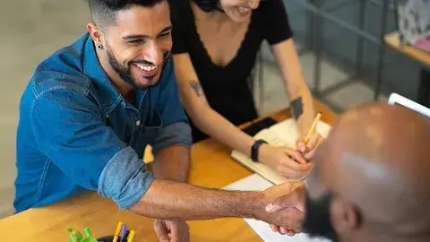 Two people shaking hands with another person