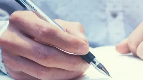 Hands writing in a notebook.