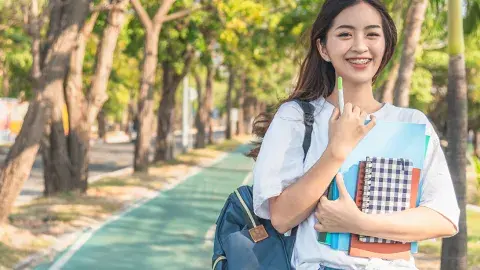 student holding notebooks and backpack