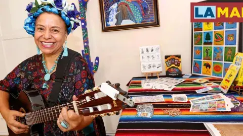 Dr. Gloria Arjona playing a guitar in a colorful room