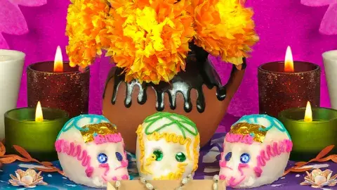 Sugar skulls and lit candles on a Day of the Dead altar
