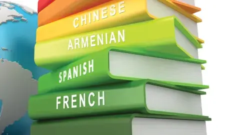 Stack of books with different languages on the spine next to a globe