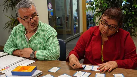man with short hair and glassess in mint green shirt working with woman with glassses short hair and red sweater