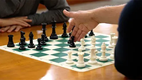 a game of chess being played by two players on a wooden table