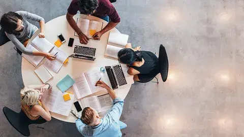 High view of circular table with students studying