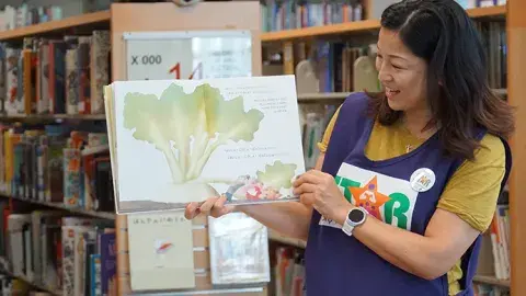 Woman wearing STAR vest holding up a book