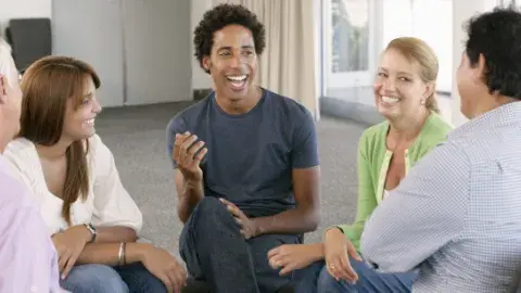 Group of adults sitting in chairs in a circle having a lively conversation