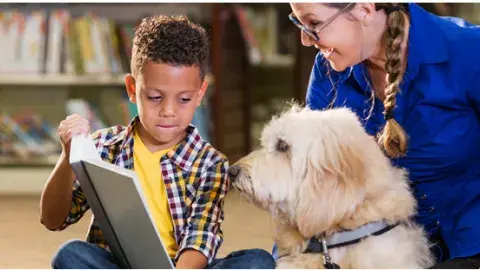 boy reading to dog with adult watching