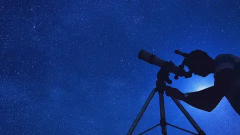 Looking up at the dark, starry night sky with a telescope  