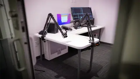 A podcast studio with desk and audio recording equipment