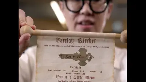 Person holds up scroll that reads "Barclay Kitchen"
