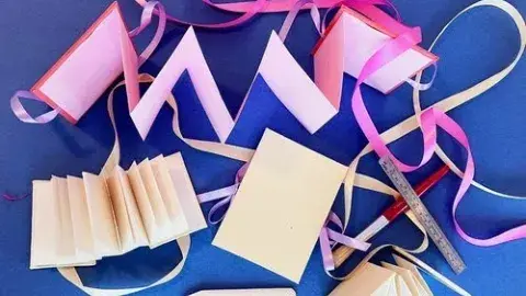 Accordion books with ribbon and bookmaking supplies on a blue background