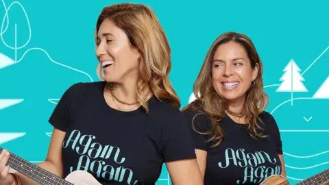 Two smiling women are holding ukuleles