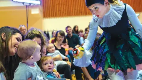 An adult female showing a toy to a baby.