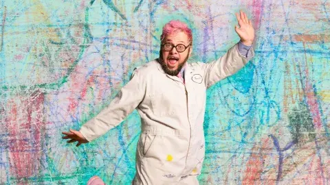 ricky rainbow beard - a person with pink hair jumping against a colorful background