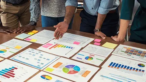 people leaning over a table looking at business spreadsheets