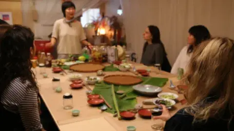 a group of people sitting around a table listening to Chef Jess Wang talk 