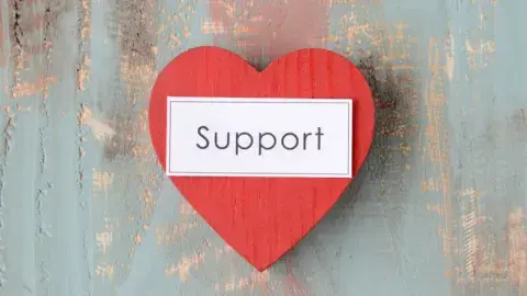 red heart with word support in black text