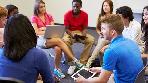 a group of teens sitting on chairs in a circle in the midst of discussion