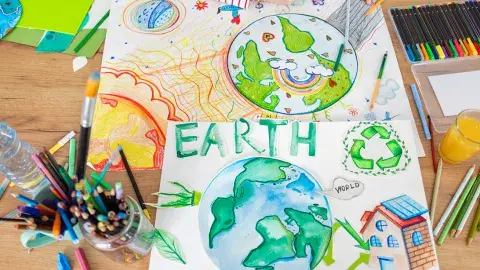 Wooden table with art supplies and drawings of planet earth.