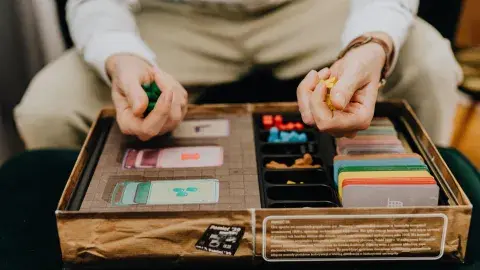 Person holding game pieces over a game board as if about to roll a turn.